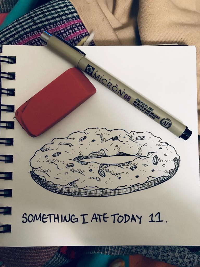 A nice looking ink sketch of a bagel, with a pen and an eraser on the sketch book